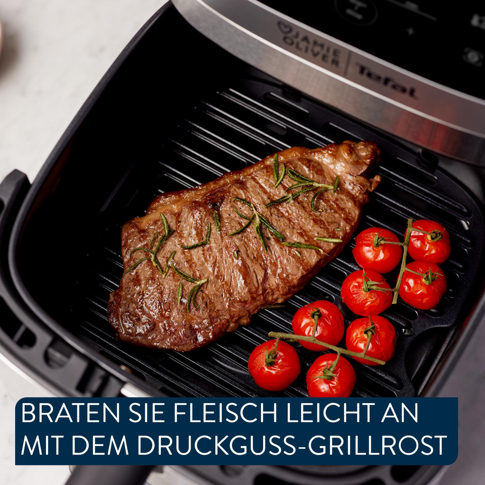 Ein gegrilltes Steak mit Rosmarin und Kirschtomaten auf einem schwarzen Grill in einer Heißluftfritteuse. Tefal und Jamie Oliver Logos.