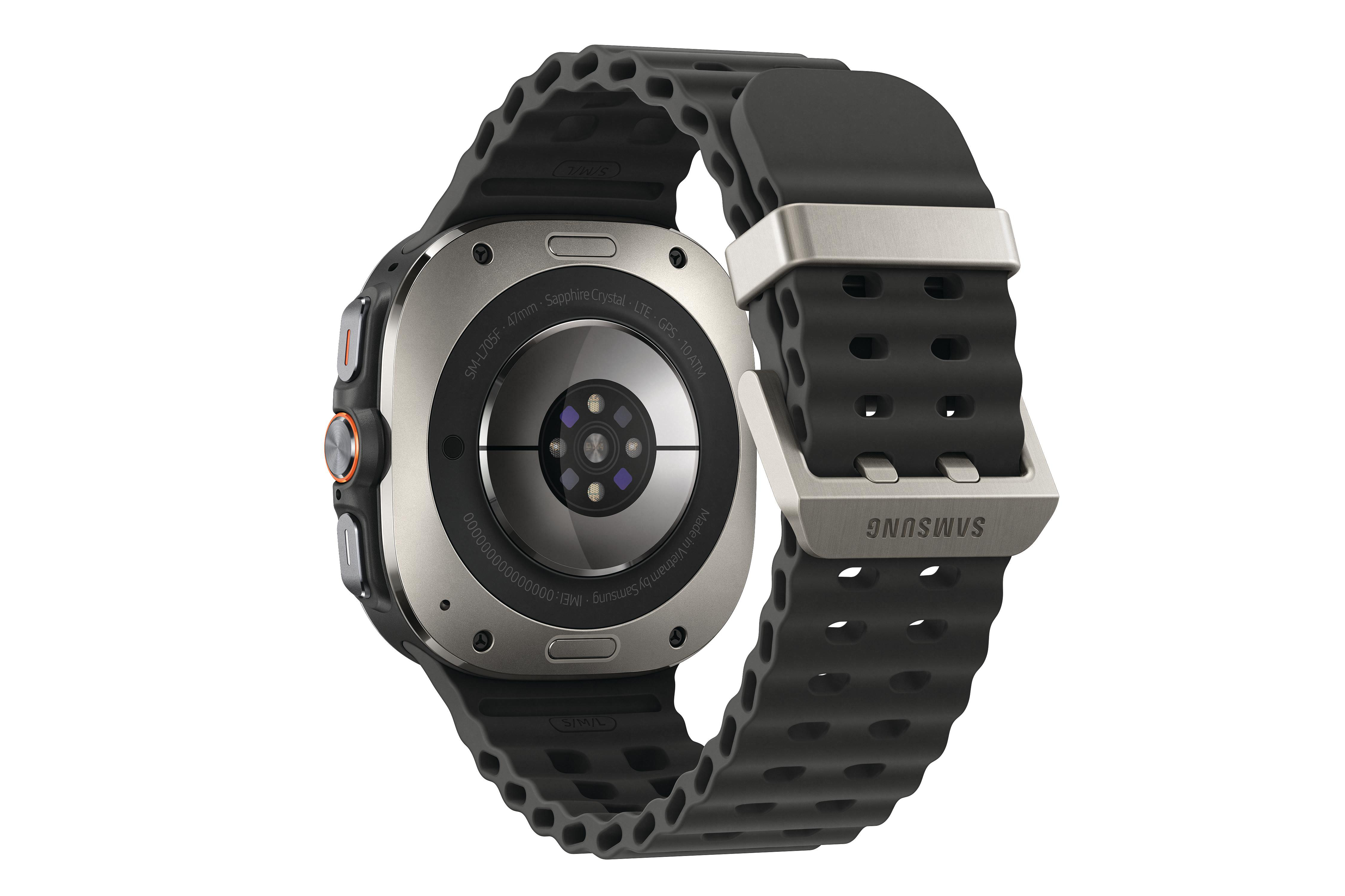 Eine schwarze und silberne Samsung Smartwatch wird von hinten gezeigt, mit angebrachtem Armband. Details umfassen Text und einen Verschluss.