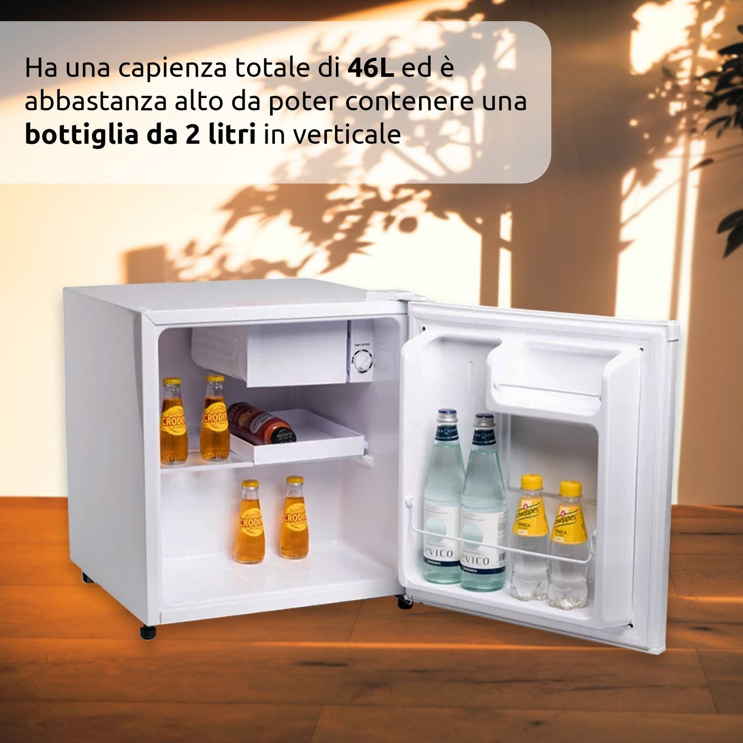 Un mini-frigo bianco con la porta aperta, che mostra bottiglie di bevande all'interno. Il frigo è su un pavimento di legno.