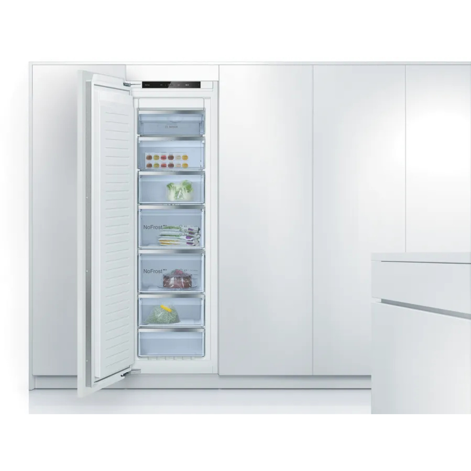 A white freezer with the door open, revealing several drawers filled with food items. It is integrated into a white wall.