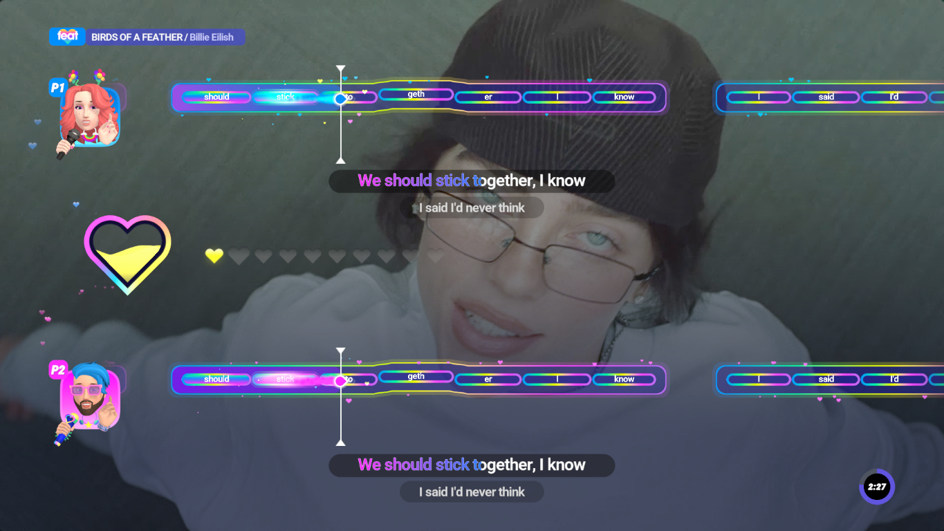 Interfejs gry muzycznej. Kobieta w okularach śpiewa. Teksty pojawiają się z kolorowymi paskami i ikonami dwóch graczy.