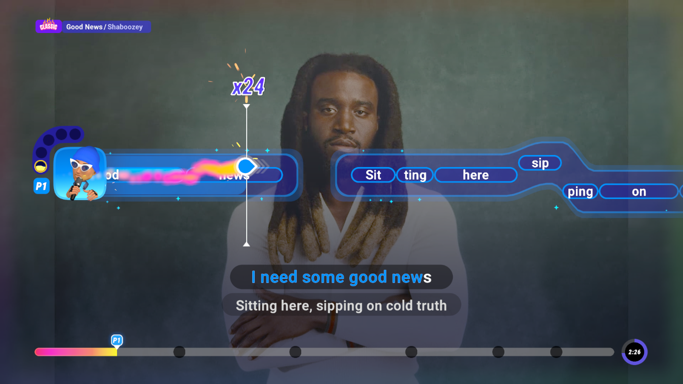 Mężczyzna z dredami śpiewa do mikrofonu. Tekst na ekranie: 'I need some good news'. Wyświetlana jest gra karaoke.