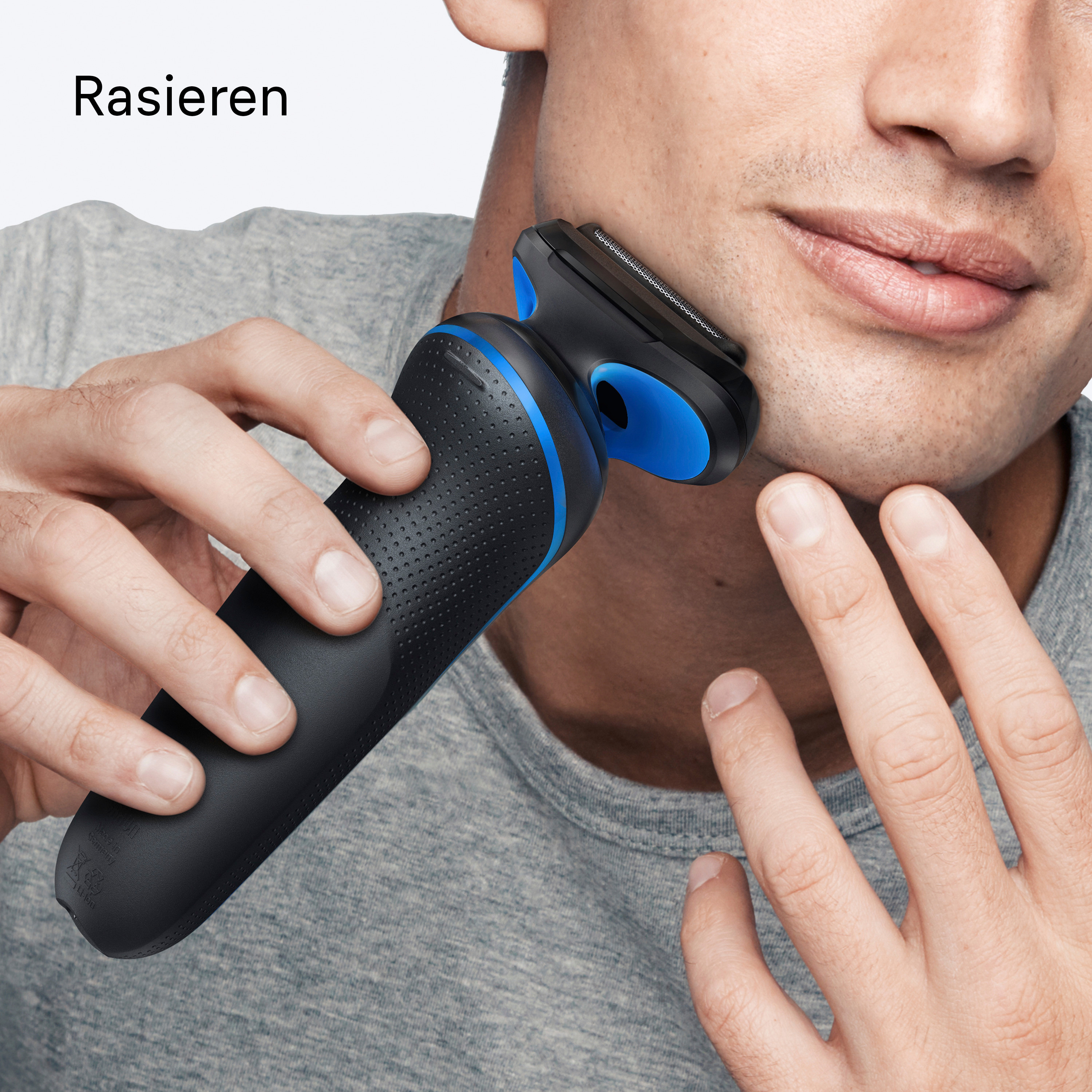 Mann rasiert sich mit einem schwarz-blauen Elektrorasierer. Nahaufnahme von Gesicht und Händen.