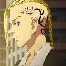 Blondhaarige Person mit Drachentattoo auf dem Kopf, trägt eine schwarze Jacke und ein weißes Hemd.