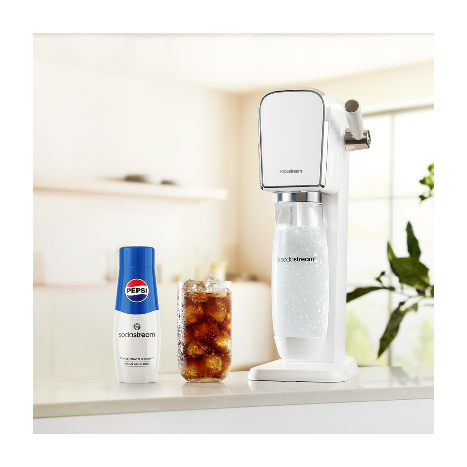 Una macchina SodaStream bianca, una bottiglia di concentrato Pepsi e un bicchiere di cola con cubetti di ghiaccio su una superficie bianca.