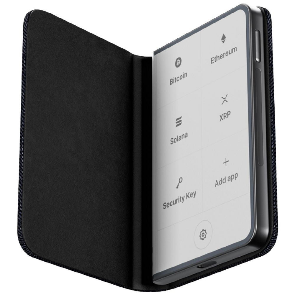 Una billetera de hardware cripto en una funda negra, mostrando opciones de criptomonedas como Bitcoin y Ethereum en su pantalla.