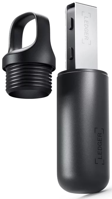 Se muestra un dispositivo USB negro con una memoria USB plateada. Está en una carcasa negra con una tapa negra a un lado. La palabra "Ledger" es visible.