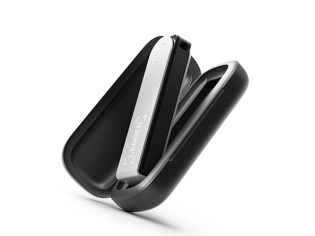 Un monedero de hardware Ledger en su estuche protector negro. El dispositivo es negro y plateado. El estuche está abierto, mostrando el Ledger.
