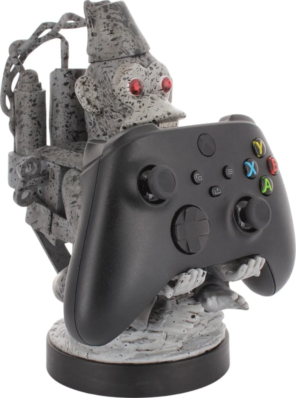Una figura grigia simile a una scimmia che tiene in mano un controller Xbox nero. La figura ha gli occhi rossi. Il controller ha pulsanti colorati.