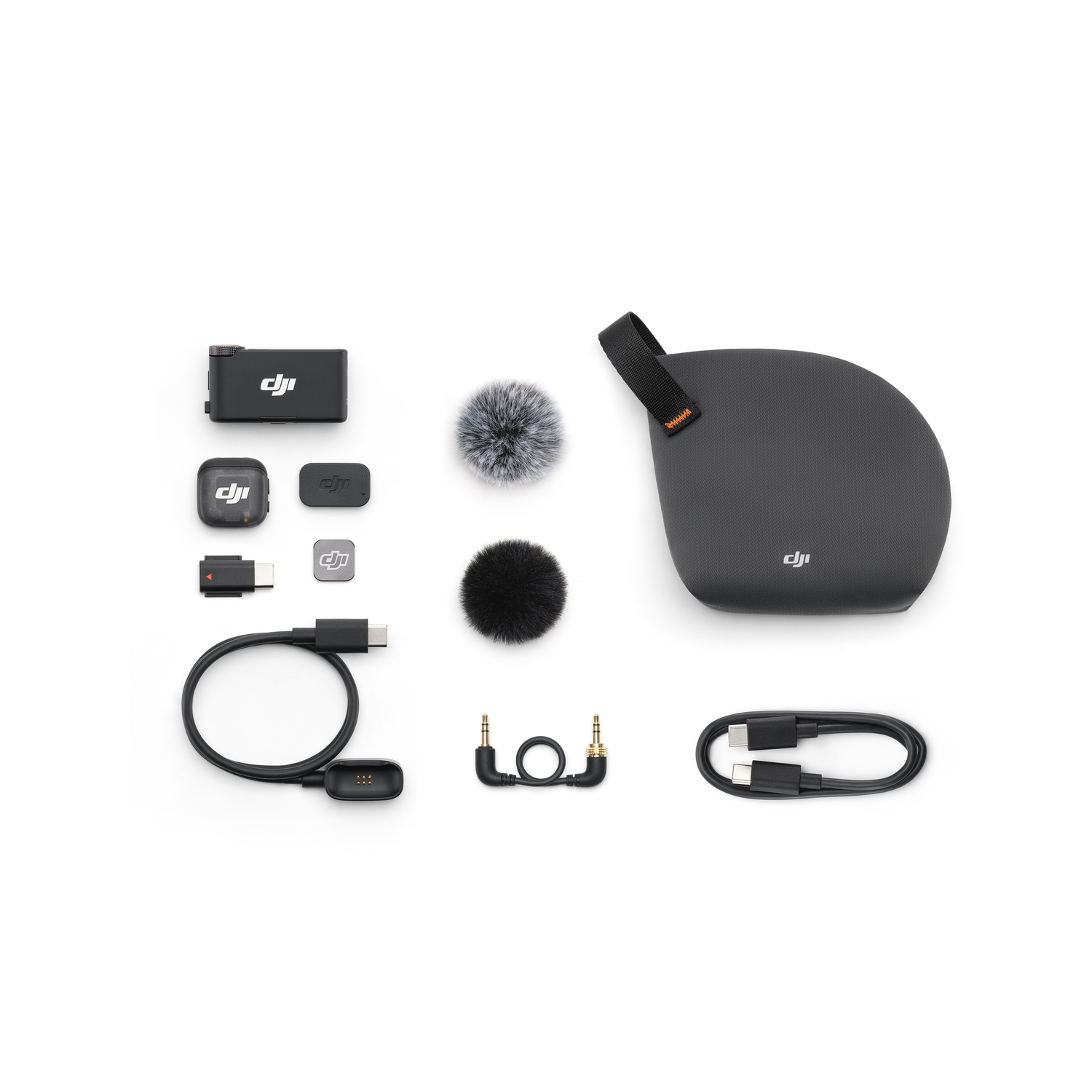 A kit of black audio equipment is laid out on a white surface, including microphones, cables, and a carrying case.