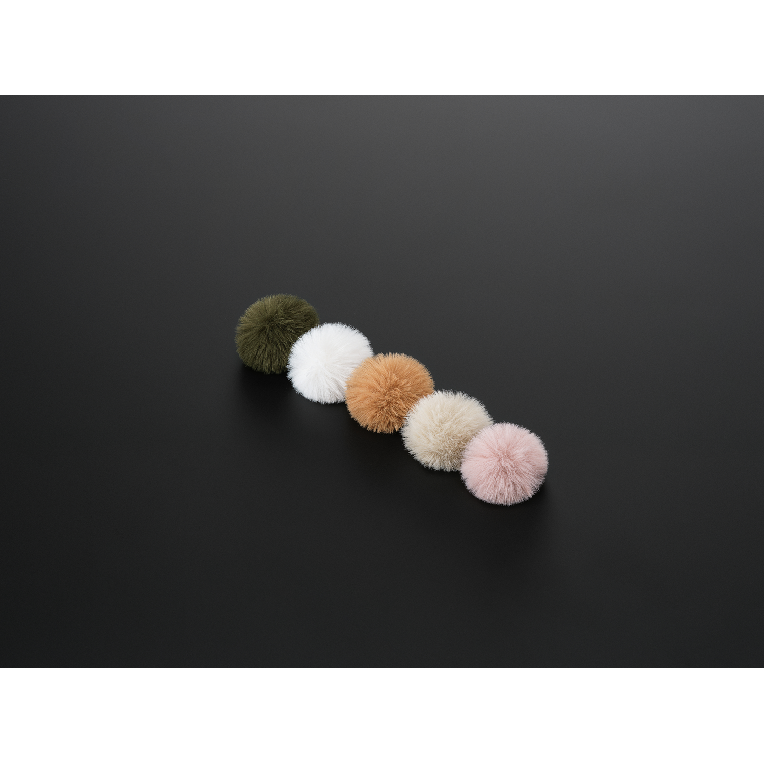 Vijf pluizige pompons in olijf, wit, bruin, beige en roze, diagonaal geplaatst op een zwarte achtergrond.