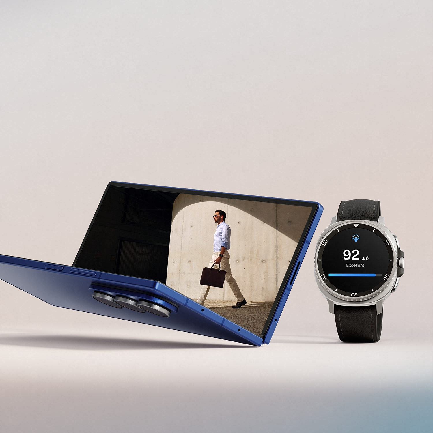 Una tableta azul con un hombre en la pantalla, junto a un reloj inteligente. El reloj muestra una puntuación de 92,6, y el hombre lleva un maletín.