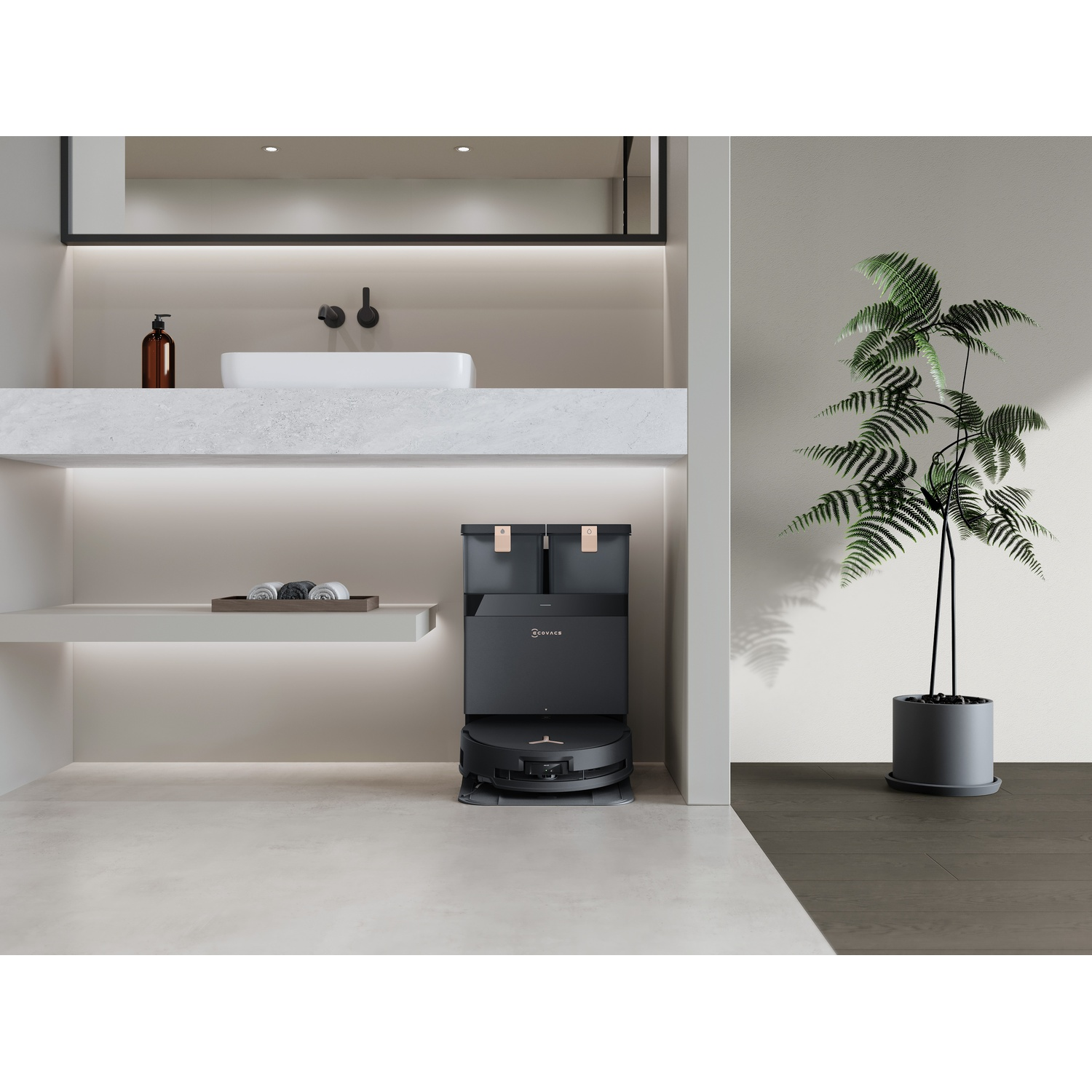 Un bagno moderno con un robot aspirapolvere. Una pianta a destra. Un lavandino e uno specchio a sinistra.