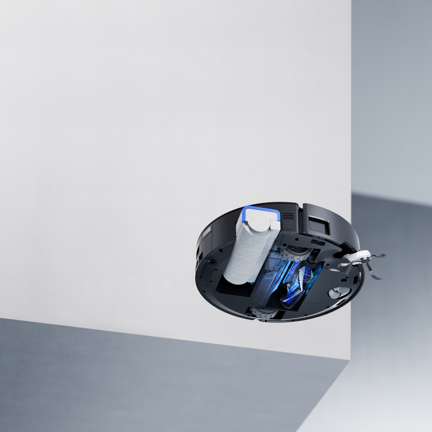 Un aspirapolvere robot nero e blu fluttua a mezz'aria. È posizionato vicino a un muro bianco e a un muro grigio.