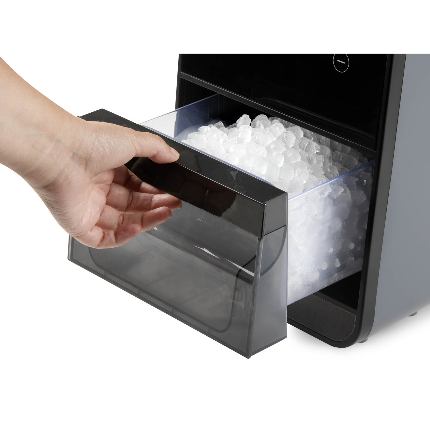 A hand pulls out an ice bin from a black and grey ice maker. The bin is full of ice cubes.