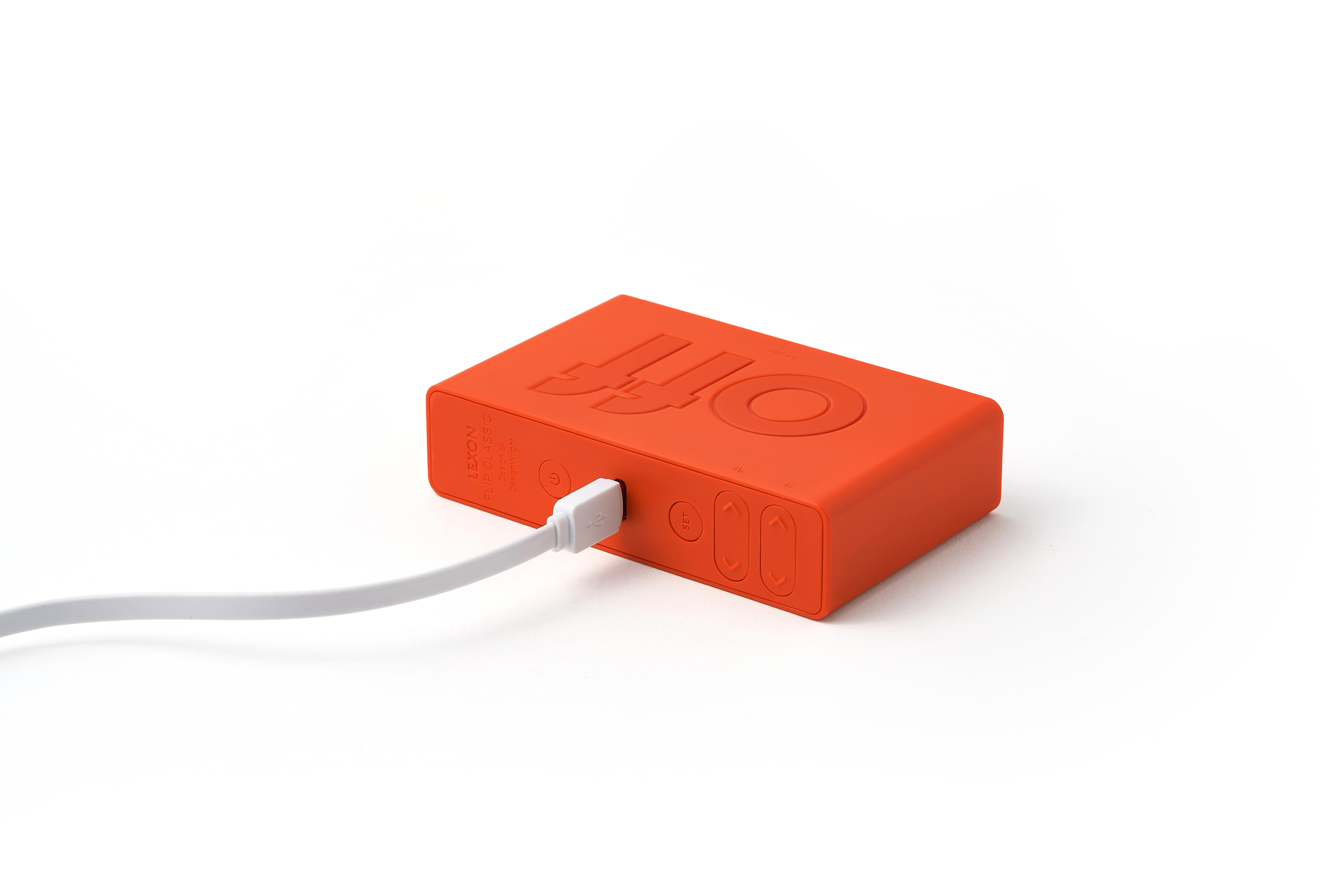 Ein orangefarbenes rechteckiges Gerät mit 'OFF' oben, weißes Kabel eingesteckt. Weißer Hintergrund.