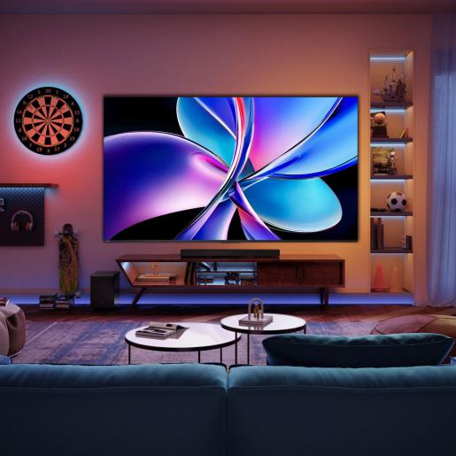 Nappali nagy TV-vel, darts-táblával és dohányzóasztalokkal. A TV absztrakt művészetet jelenít meg.