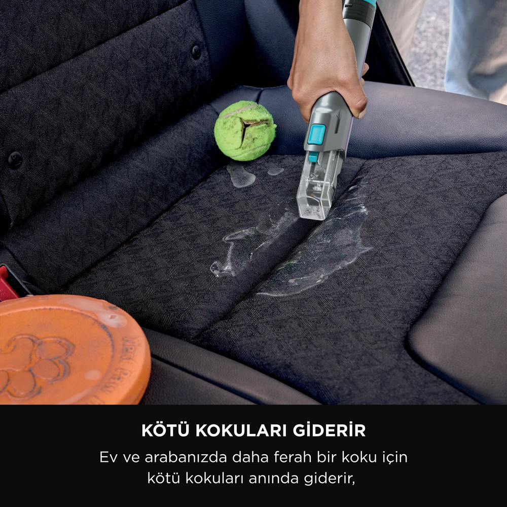 Bir kişi bir araba koltuğunu elektrik süpürgesiyle temizliyor. Bir tenis topu ve bir frizbi koltuğun yakınında.