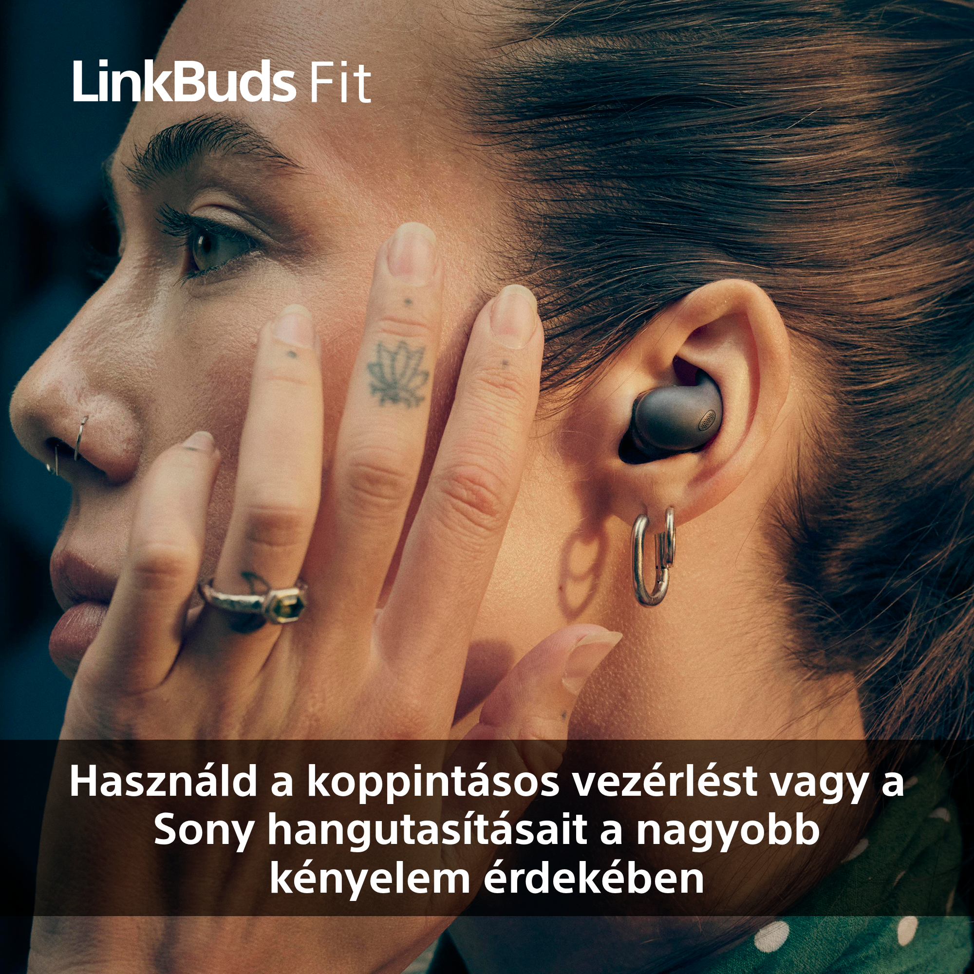 Egy személy, akinek fülhallgató van a fülében. Tetoválásai, gyűrűi és orrkarikája van. A szöveg szerint használja az érintésvezérlést.