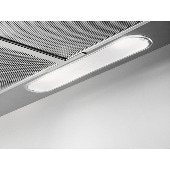 Nahaufnahme einer Küchenabzugshaube. Sie hat ein helles Licht und ein Metallgitterfilter. Der Hintergrund ist eine schlichte weiße Wand.