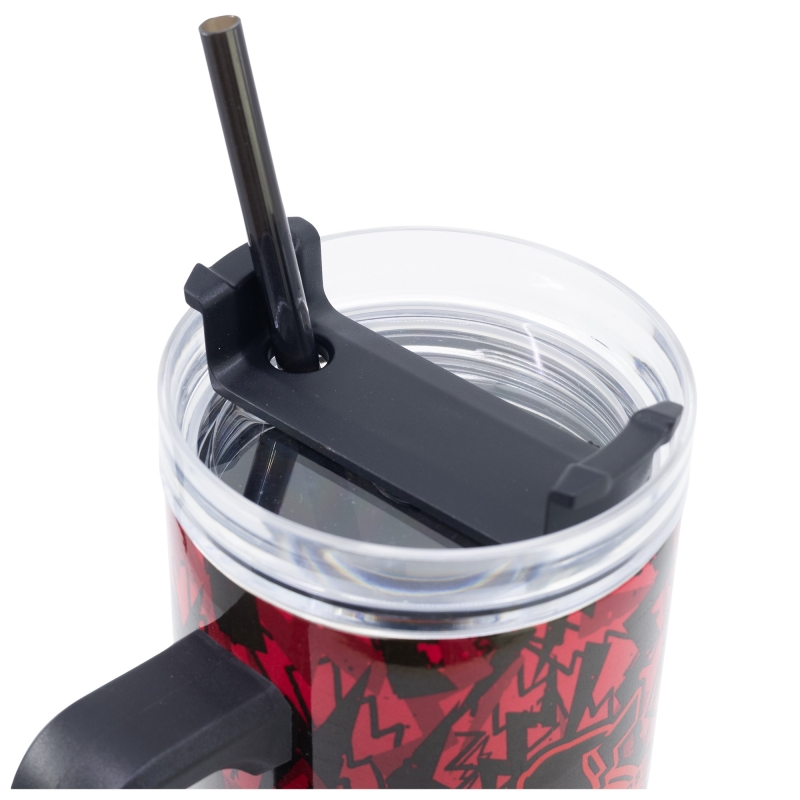 Primer plano de una taza con asa y tapa negras. Una pajita negra está insertada en la tapa. La taza es roja con diseños negros.