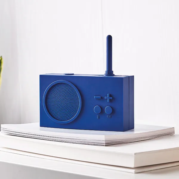 Ein blaues Retro-Radio steht auf weißen Büchern. Das Radio hat eine Antenne, einen Lautsprecher und Bedienelemente.