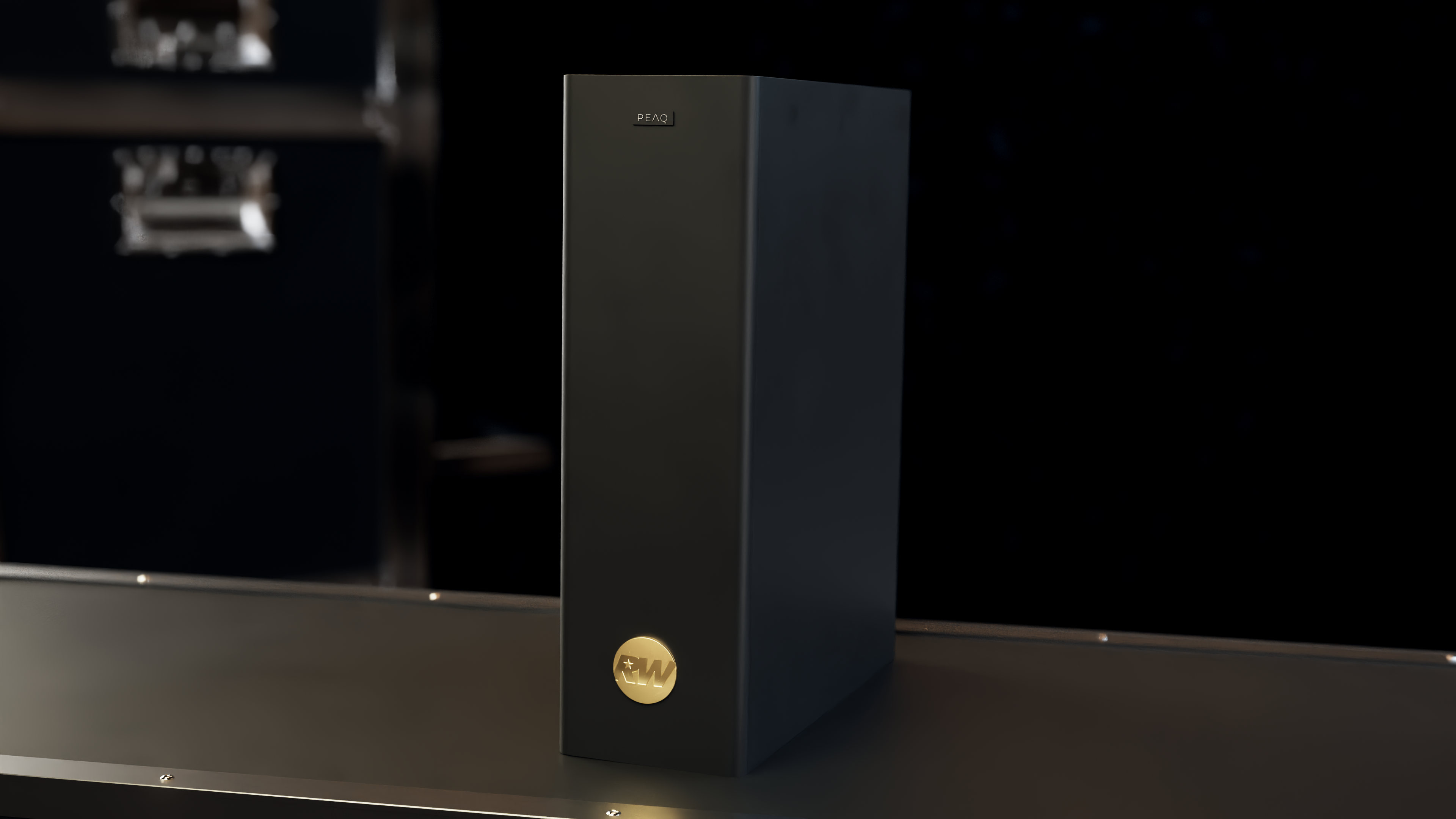 Wysoki, czarny głośnik stoi na powierzchni. Ma złote logo i napis PEAQ. Tło jest ciemne.