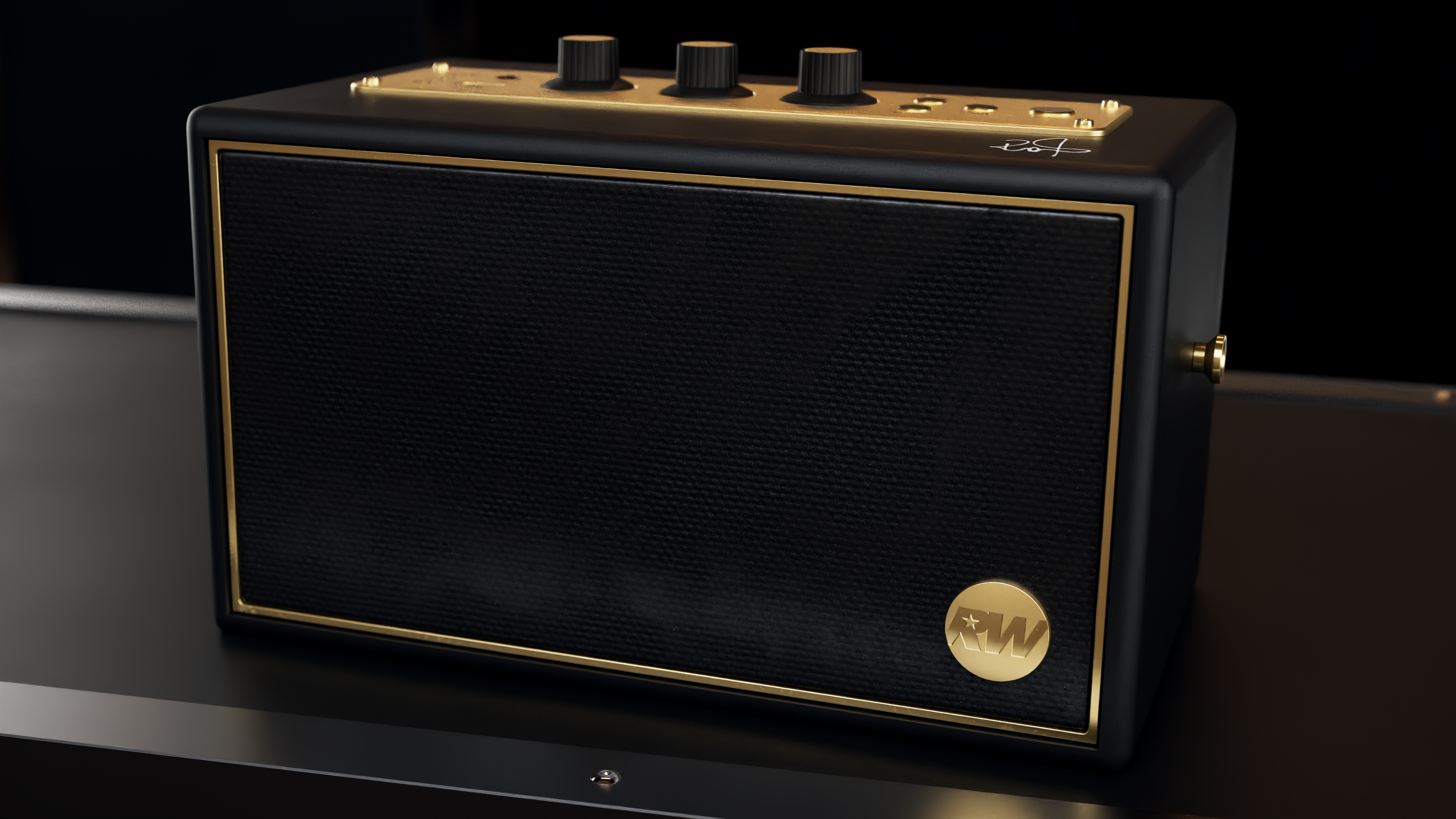 Czarny prostokątny głośnik ze złotymi akcentami. Ma teksturowany przód, pokrętła i złote logo.