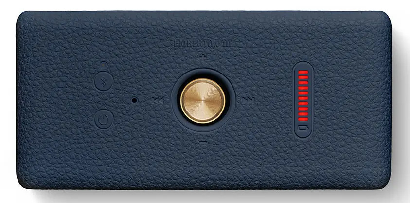 Granatowy głośnik z mosiężnym pokrętłem i czerwonymi wskaźnikami świetlnymi. Posiada przyciski zasilania, Bluetooth i odtwarzania.