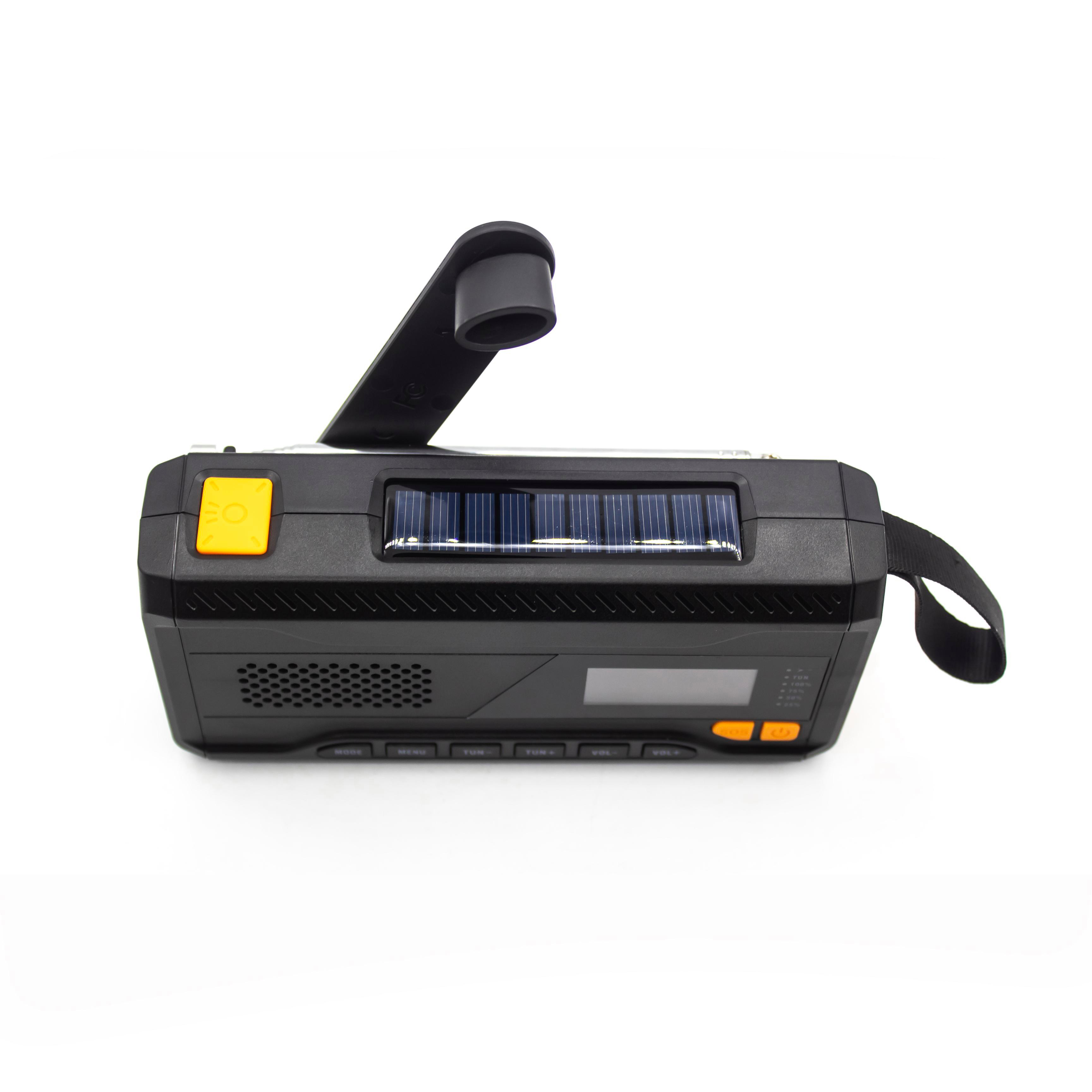 Schwarzes Kurbelradio mit Solarpanel. Gelbe Knöpfe, schwarzer Griff und Riemen. Isoliert auf weißem Hintergrund.