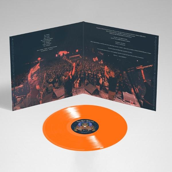 Eine orangefarbene Schallplatte liegt vor einem geöffneten Albumcover, das eine Band zeigt, die auf der Bühne vor einem Publikum auftritt.