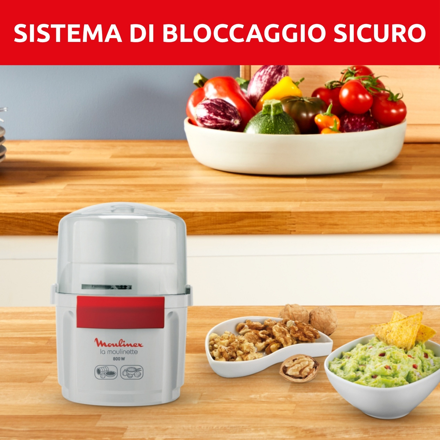 Un robot da cucina Moulinex e ciotole di verdure, guacamole e noci su una superficie di legno. In alto, il testo dice 'Sistema di bloccaggio sicuro'.