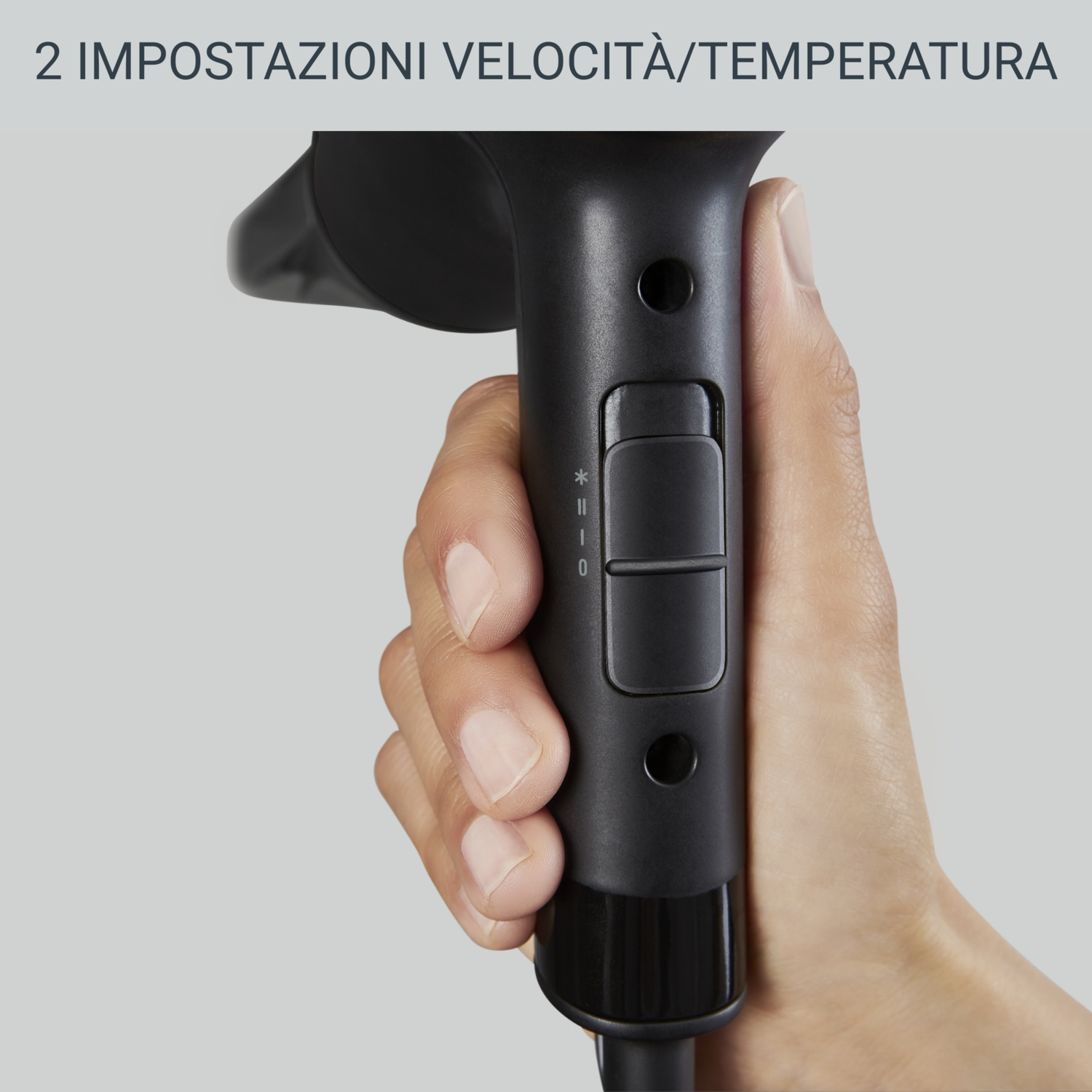 Mano che tiene un asciugacapelli nero. L'asciugacapelli ha pulsanti e impostazioni. Lo sfondo è grigio chiaro.