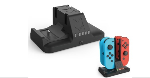 Base de carga negra con puerto USB-C. Joy-Cons, azul y rojo, en una base más pequeña. Fondo blanco.