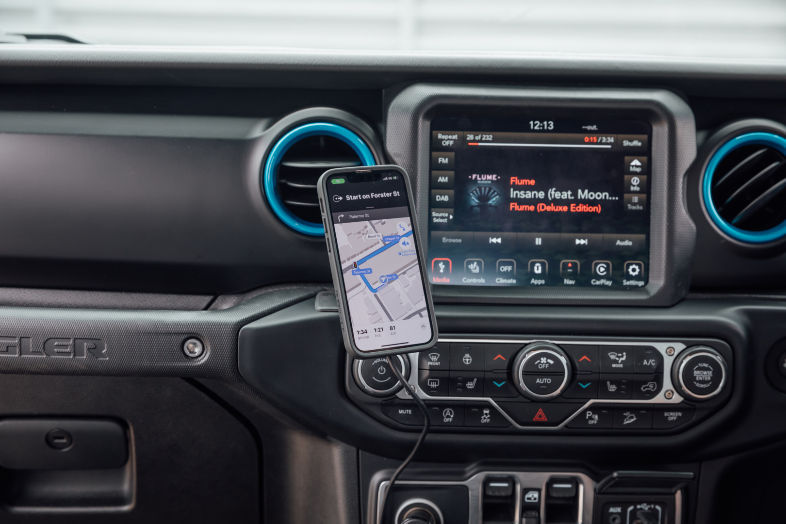 Im Auto: Telefon mit Karte, Armaturenbrett mit Radio, Lüftungsschlitzen und Autosteuerung. Telefon zeigt Route.