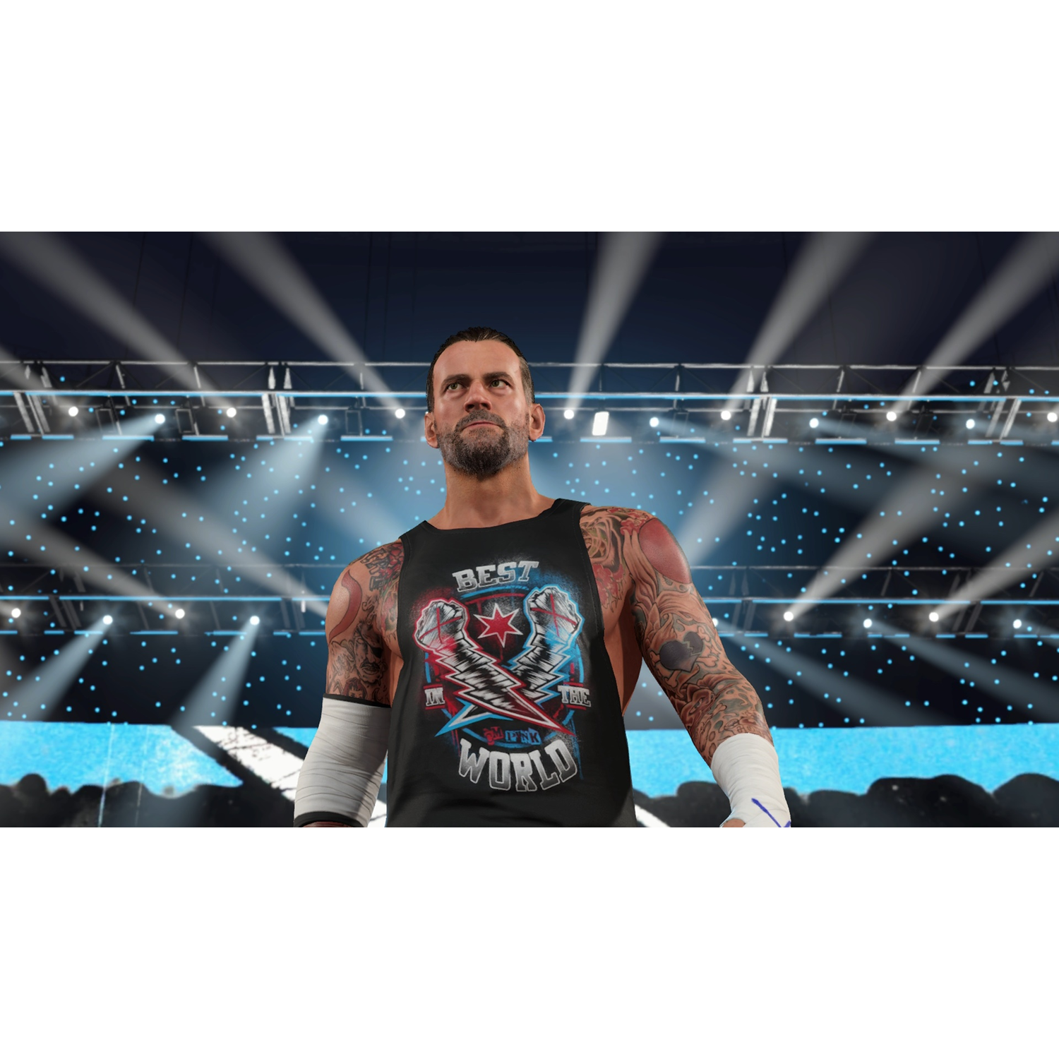 Een worstelaar in een zwarte tanktop met tatoeages staat onder heldere lichten. Op de shirt staat 'Best in the World'. Podiumverlichting op de achtergrond.
