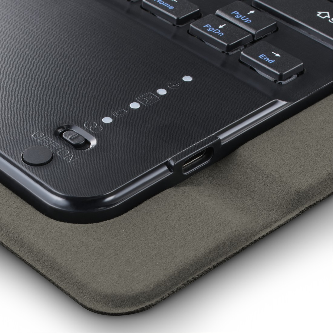 Nahaufnahme einer schwarzen Tastatur mit Steuertasten und einem Ein/Aus-Schalter. Sie liegt auf einem grauen Pad. USB-C-Anschluss sichtbar.
