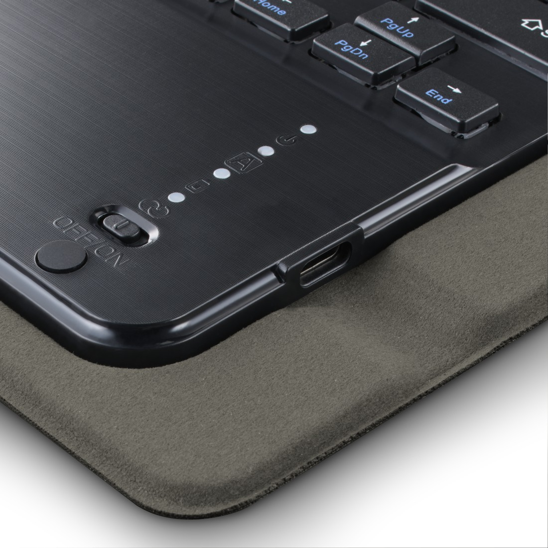 Nahaufnahme einer schwarzen Tastatur mit Netzschalter, Kontrollleuchten und USB-Anschluss. Sie liegt auf einer grauen, strukturierten Oberfläche.