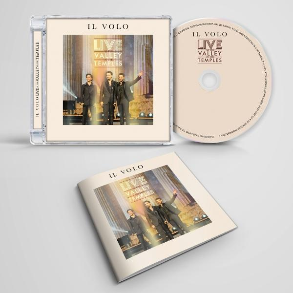 Eine offene CD-Hülle, CD und ein Booklet zeigen ein IL VOLO-Konzert. Die Band steht auf der Bühne. CD-Hülle und CD sind hell.