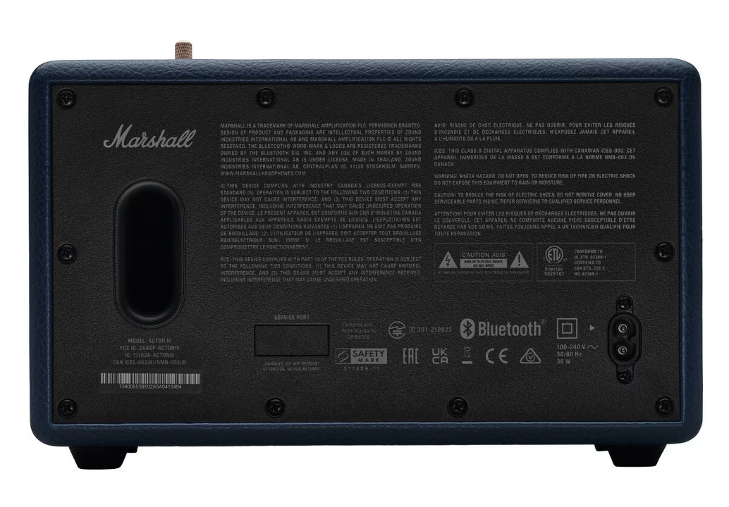 Czarny tył głośnika. Zawiera loga, ostrzeżenia, porty i szczegóły techniczne. Niebieska tekstura imitująca skórę otacza panel tylny.