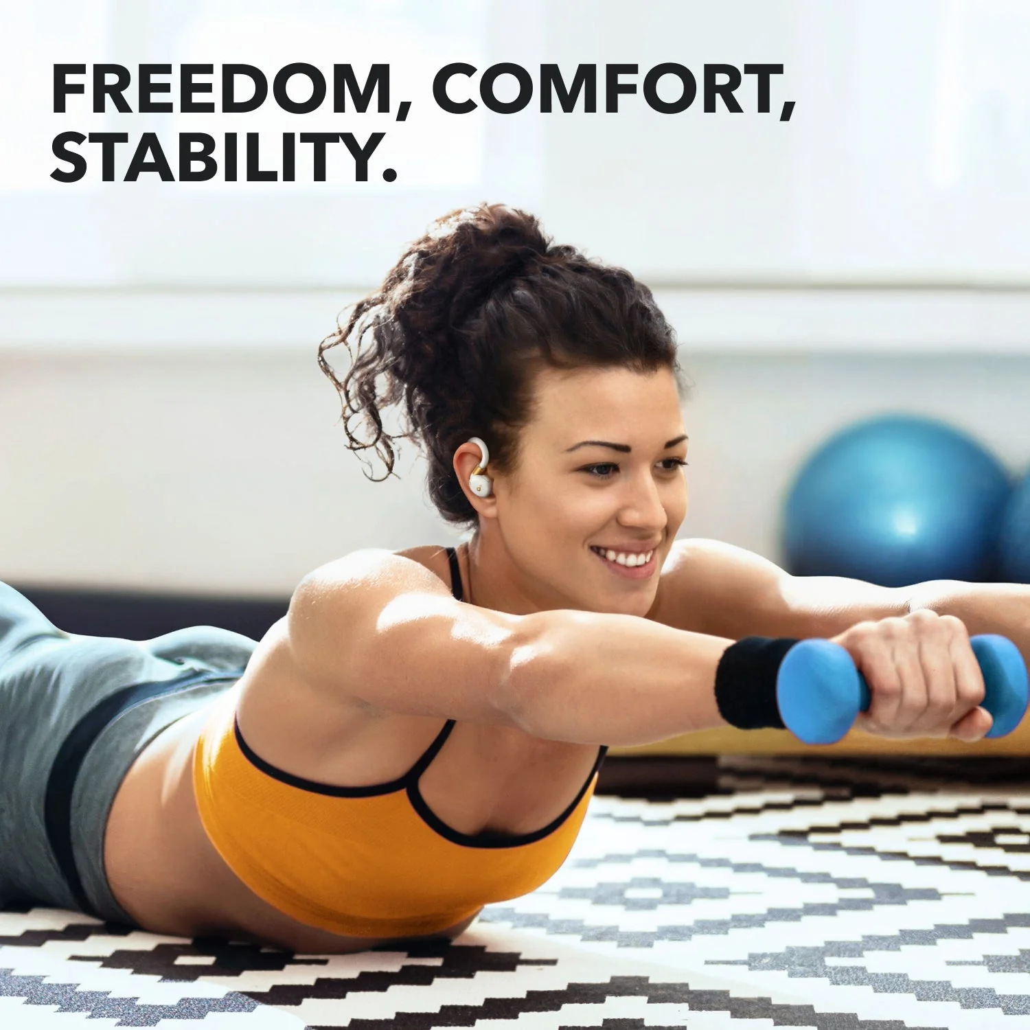 Kobieta w stroju sportowym ćwiczy z hantlami. Tekst powyżej brzmi: Wolność, komfort, stabilność.