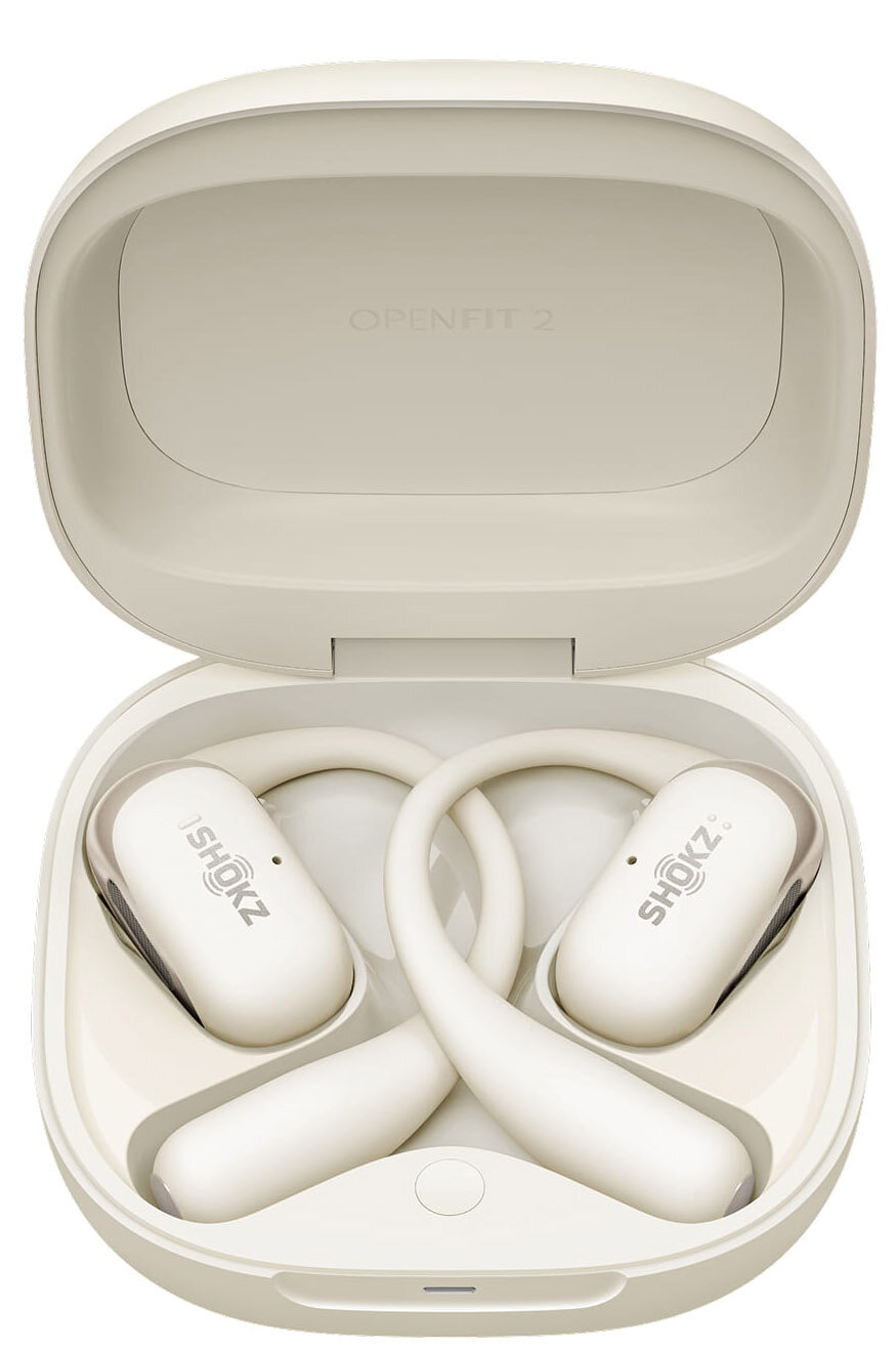 Kremowe słuchawki Shokz OpenFit 2 w pasującym etui. Etui jest otwarte, pokazując słuchawki i logo Shokz.