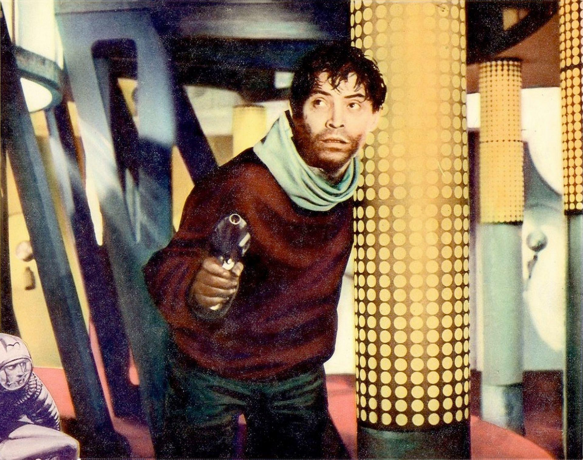 Mann mit einer Pistole in einem weinroten Pullover und grünem Schal. Futuristisches Interieur mit kreisförmig gemusterten Säulen und einem Raumfahrer.
