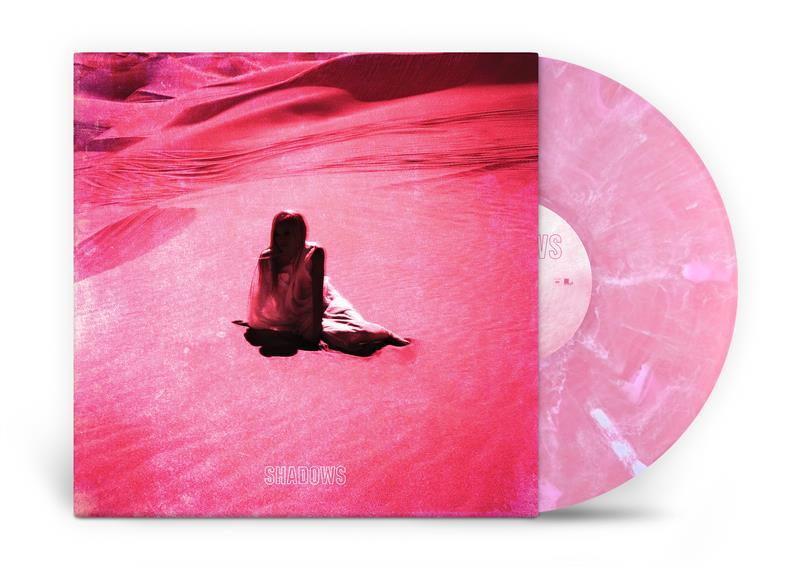 Rosa Albumcover. Eine Frau sitzt im rosa Sand. Rosa Vinyl-Schallplatte mit 'SHADOWS'. Rosa Dünen im Hintergrund.