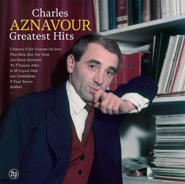 Charles Aznavour Albumcover. Er lehnt sich an ein Bücherregal. Er trägt einen Anzug und eine rote Krawatte. Albumtitel ist 'Greatest Hits'.