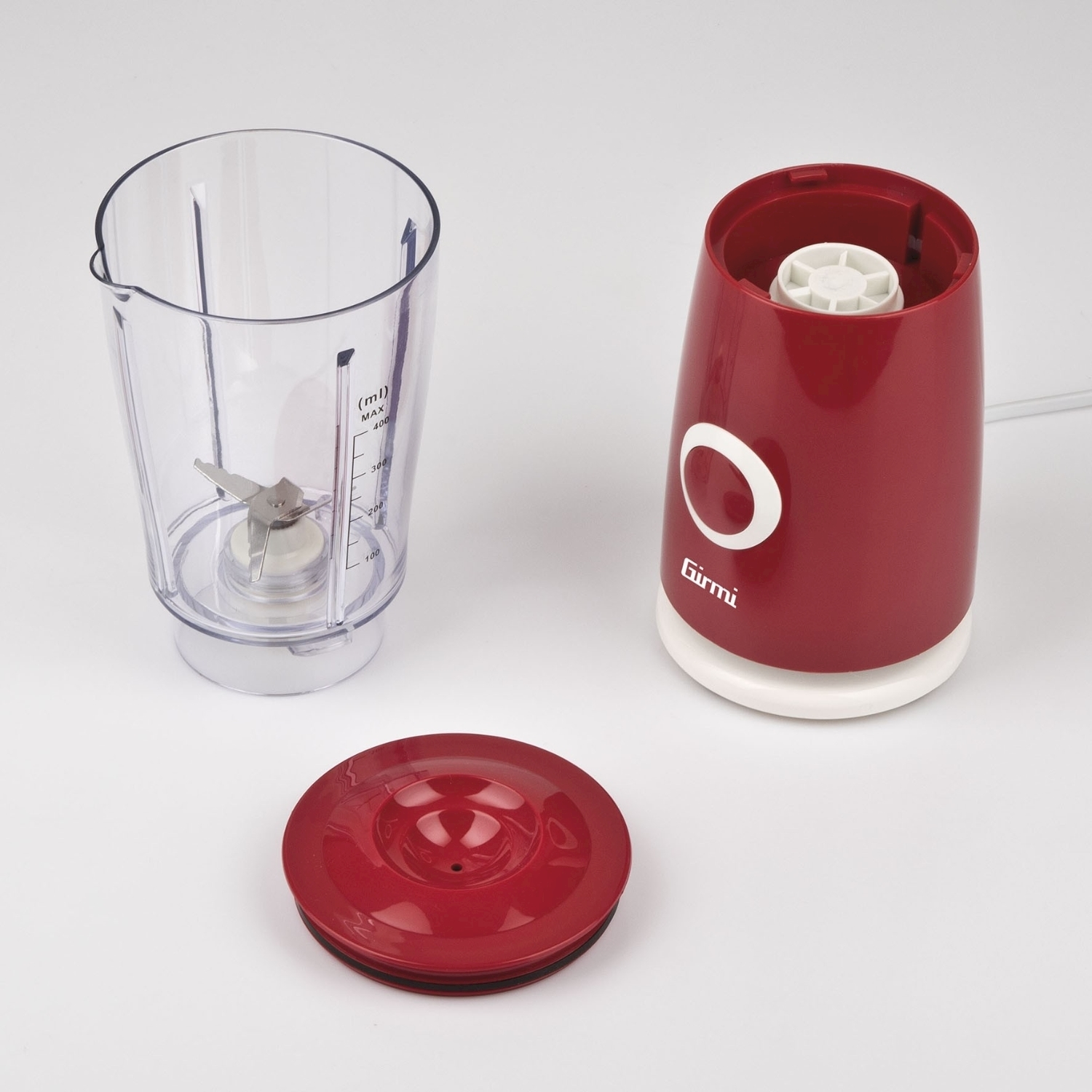 Un frullatore rosso e bianco smontato su una superficie bianca. Componenti: lama, caraffa, coperchio e base motore.