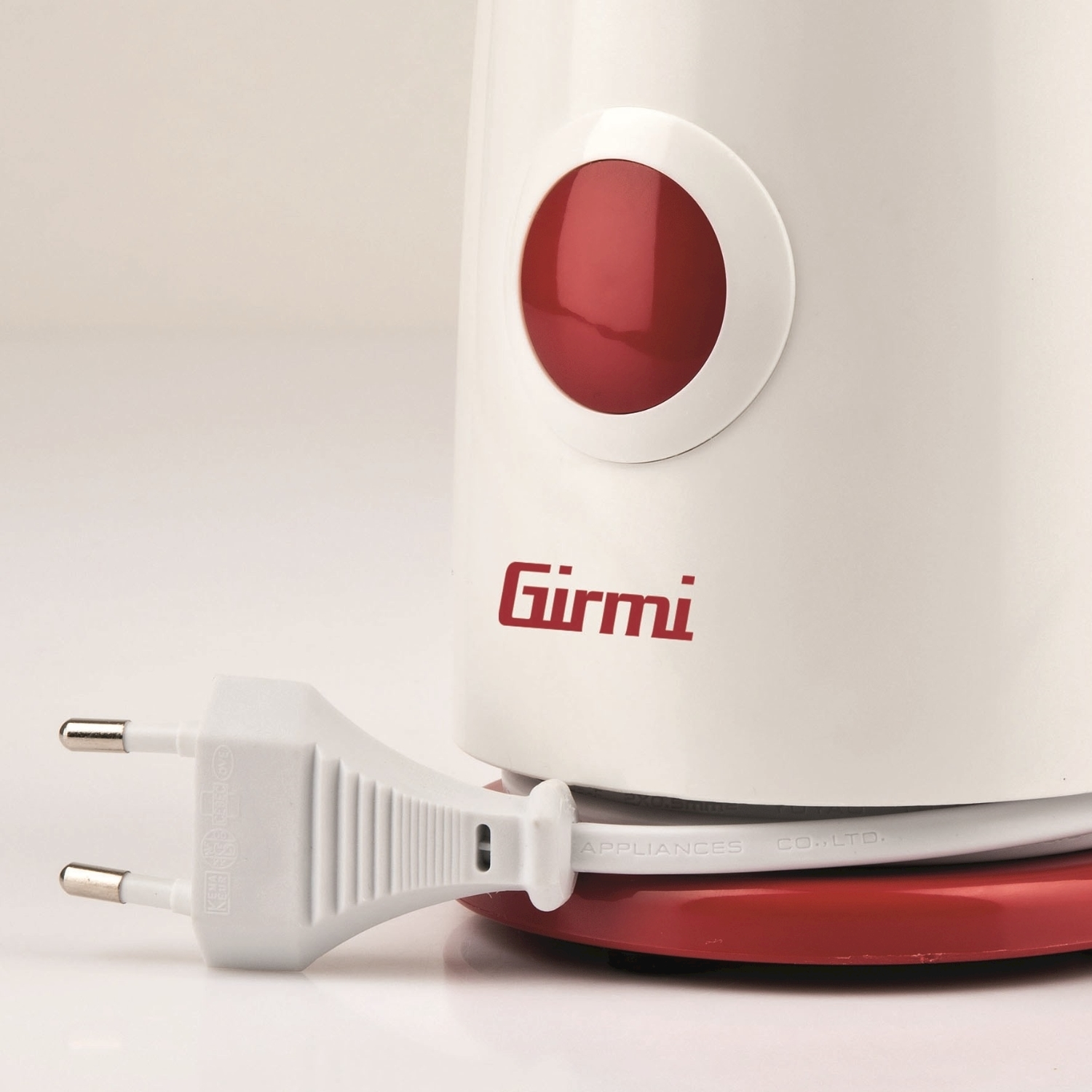 Un elettrodomestico Girmi bianco e rosso con spina. L'elettrodomestico ha un pulsante e una base rossi. La spina è bianca con due perni.