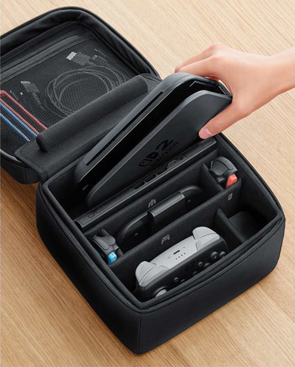 Eine schwarze Tragetasche ist geöffnet und zeigt eine Nintendo Switch-Konsole, Controller und Zubehör. Eine Hand hält die Konsole.