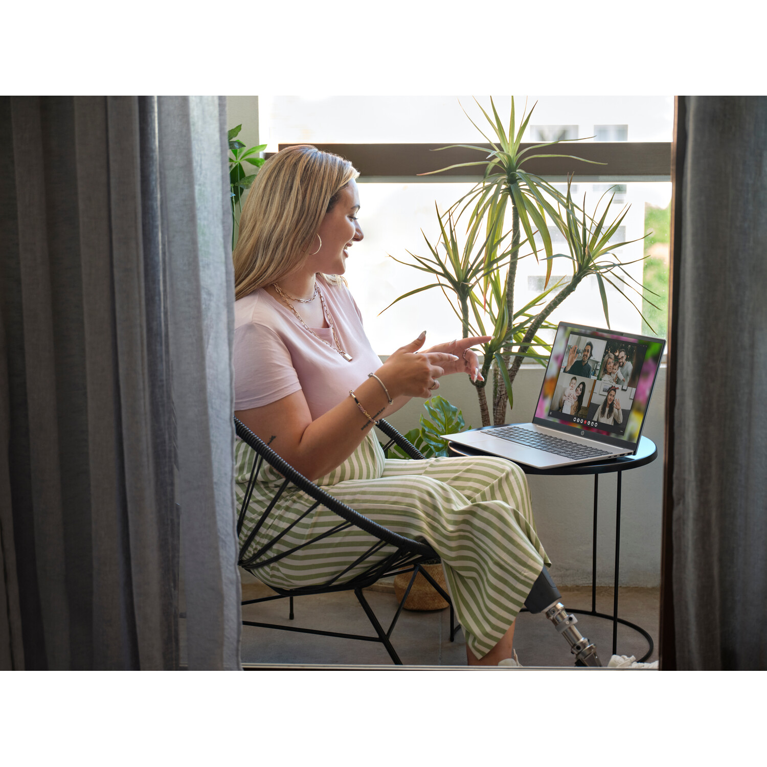 Woman on a video call. She is pointing at the laptop screen. She has a prosthetic leg.