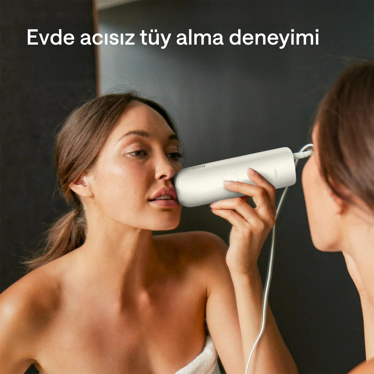 Bir kadın, aynaya bakarken yüzüne beyaz bir epilatör uyguluyor. Metinde 'Evde acısız tüy alma deneyimi' yazıyor.